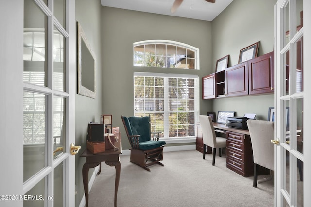 office featuring french doors, light colored carpet, ceiling fan, and a towering ceiling