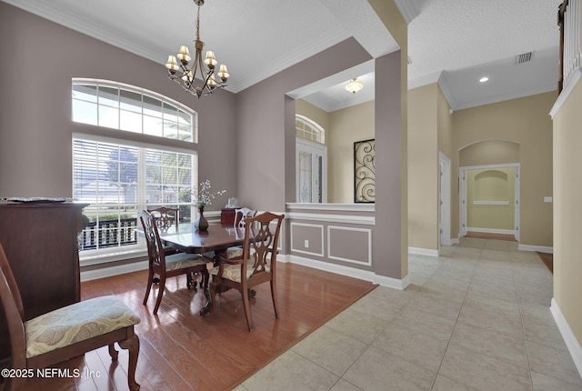 dining area featuring baseboards, visible vents, an inviting chandelier, crown molding, and light wood-type flooring