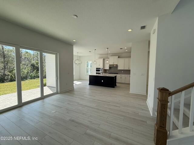 35 Mahogany Way, Palm Coast, FL 32164 - unfurnished living room with a chandelier, a textured ceiling, and light hardwood / wood-style flooring