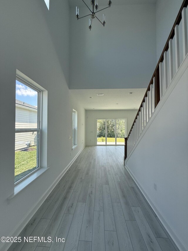 35 Mahogany Way, Palm Coast, FL 32164 - unfurnished living room with an inviting chandelier, a towering ceiling, and light hardwood / wood-style floors
