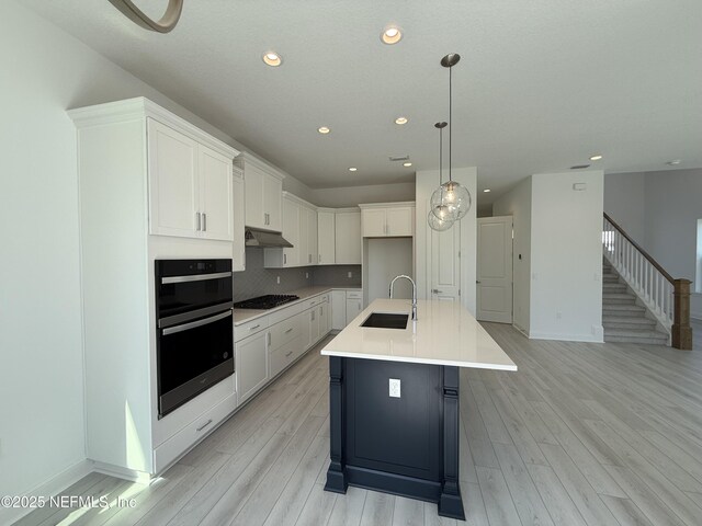 35 Mahogany Way, Palm Coast, FL 32164 - kitchen featuring decorative light fixtures, white cabinetry, sink, a kitchen island with sink, and gas stovetop