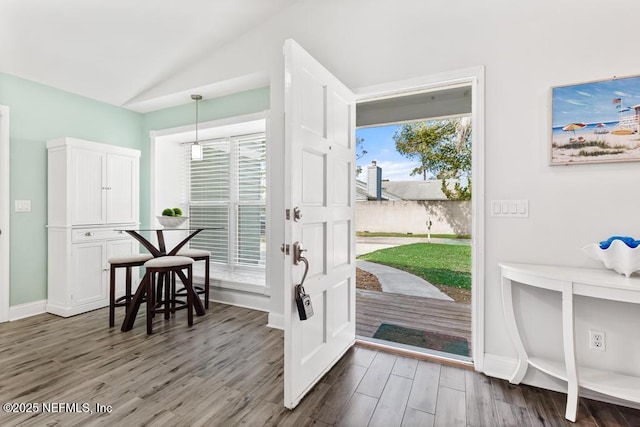 doorway featuring vaulted ceiling, dark wood-type flooring, and baseboards