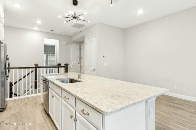 kitchen with a kitchen island with sink, white cabinetry, stainless steel appliances, and a sink