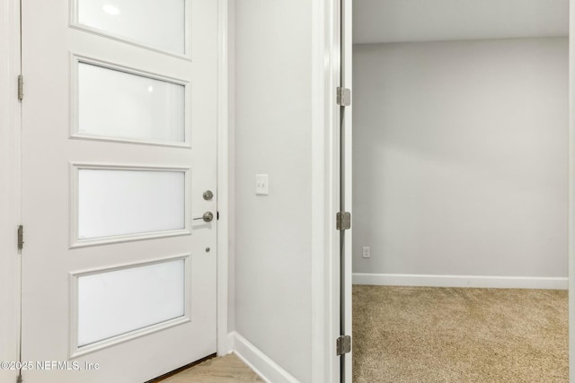 doorway featuring baseboards and light colored carpet