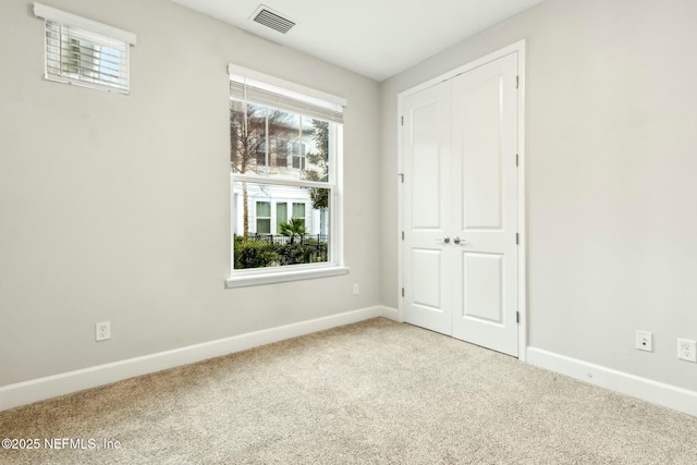 carpeted spare room featuring baseboards and visible vents