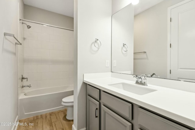 bathroom with toilet,  shower combination, wood finished floors, and vanity