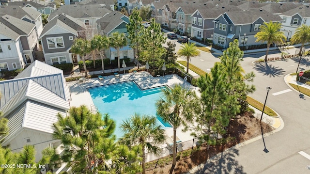 community pool featuring a patio area, fence, and a residential view