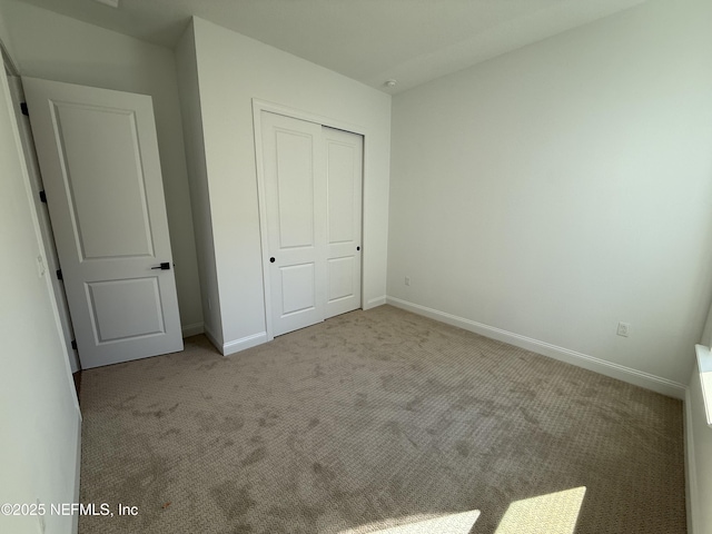 unfurnished bedroom featuring light colored carpet and a closet