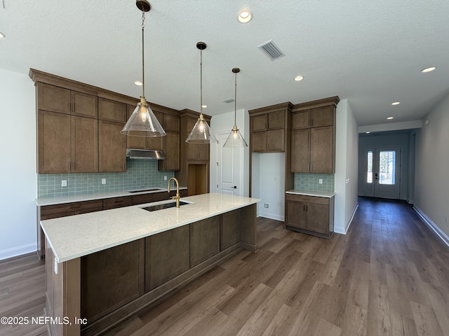 kitchen featuring pendant lighting, sink, a kitchen island with sink, and dark hardwood / wood-style floors