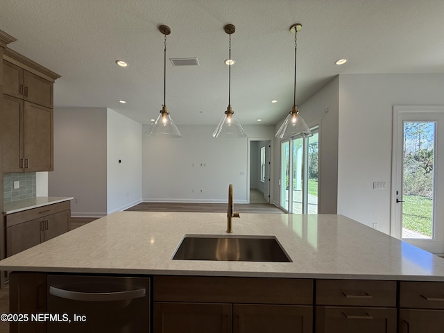 kitchen featuring tasteful backsplash, light stone countertops, sink, and a kitchen island with sink