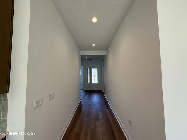 corridor with dark hardwood / wood-style floors and a textured ceiling