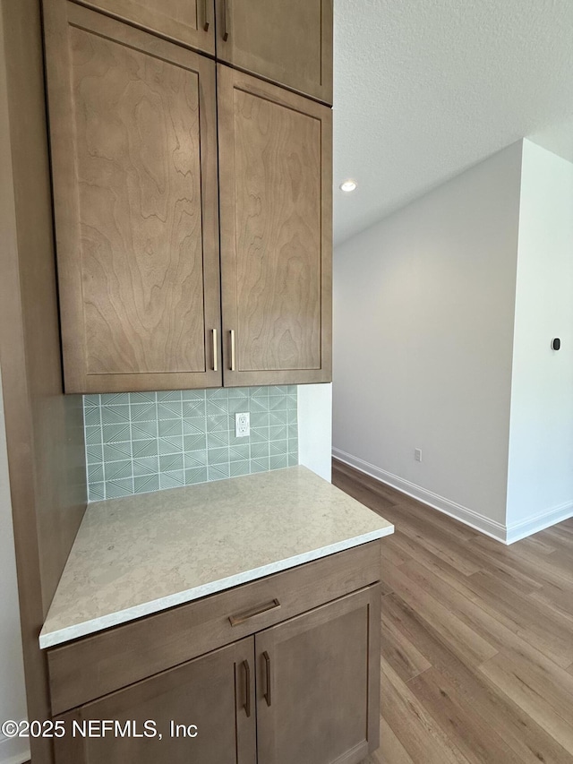 room details featuring hardwood / wood-style flooring, decorative backsplash, and a textured ceiling