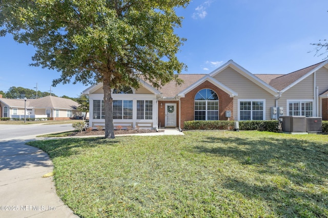 ranch-style home with a front lawn, central AC, and brick siding