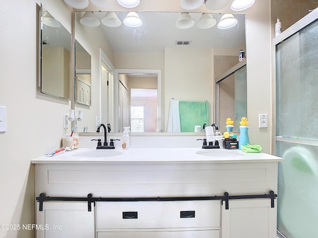 full bathroom featuring double vanity, a stall shower, a sink, and visible vents