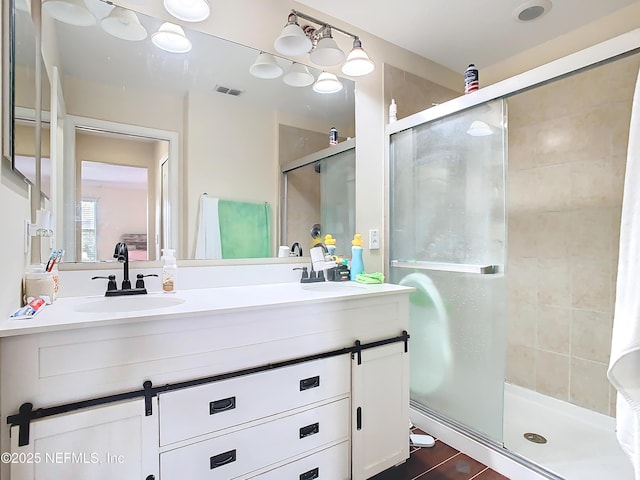 full bath with double vanity, a stall shower, visible vents, and a sink