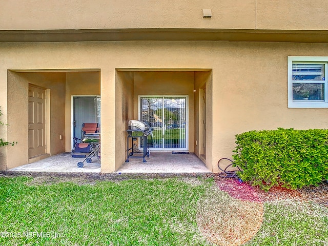 doorway to property with a yard and stucco siding