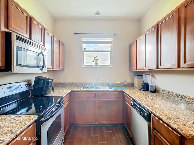 kitchen with appliances with stainless steel finishes, wood tiled floor, a sink, and light stone counters