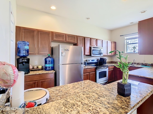 kitchen featuring appliances with stainless steel finishes, recessed lighting, a sink, and light stone countertops