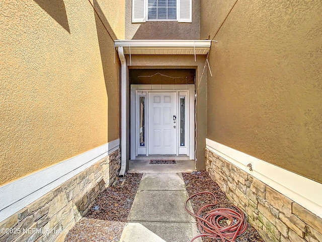 property entrance featuring stone siding and stucco siding