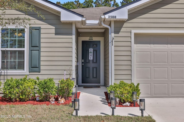 view of exterior entry featuring a garage and a shingled roof