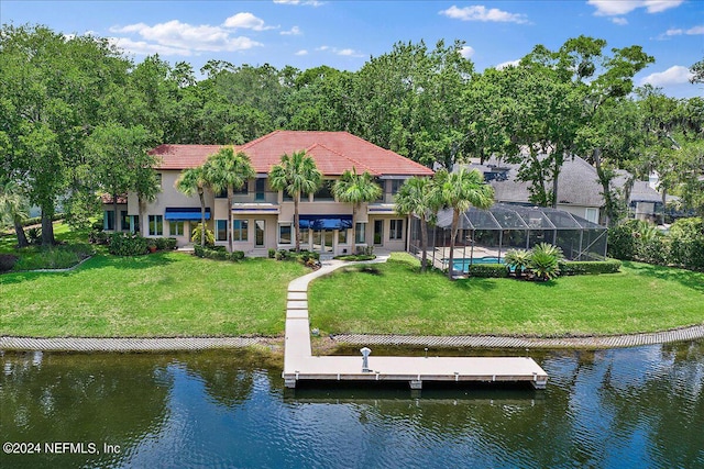 rear view of house featuring a water view, a lanai, and a lawn