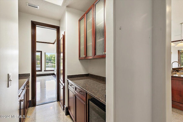 13612 Mcqueens Ct, Jacksonville, FL 32225 - bar featuring dark stone countertops, a textured ceiling, and decorative light fixtures