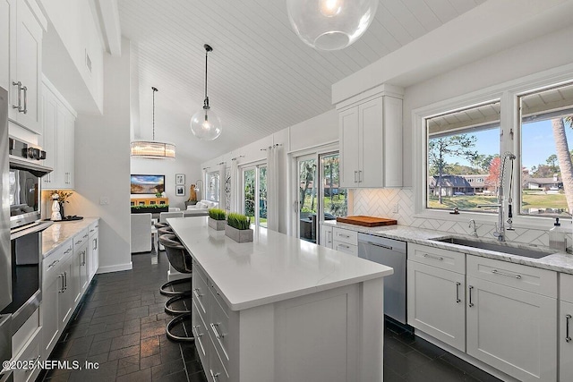 kitchen featuring decorative backsplash, appliances with stainless steel finishes, open floor plan, white cabinets, and a kitchen island