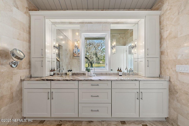 bathroom with a sink, tile walls, and double vanity