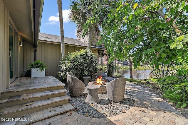 view of patio with a water view and a fire pit