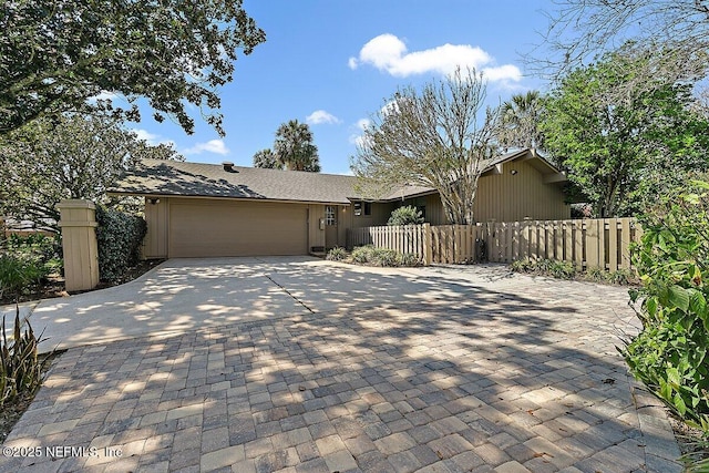 view of front of home featuring a garage, decorative driveway, and a fenced front yard