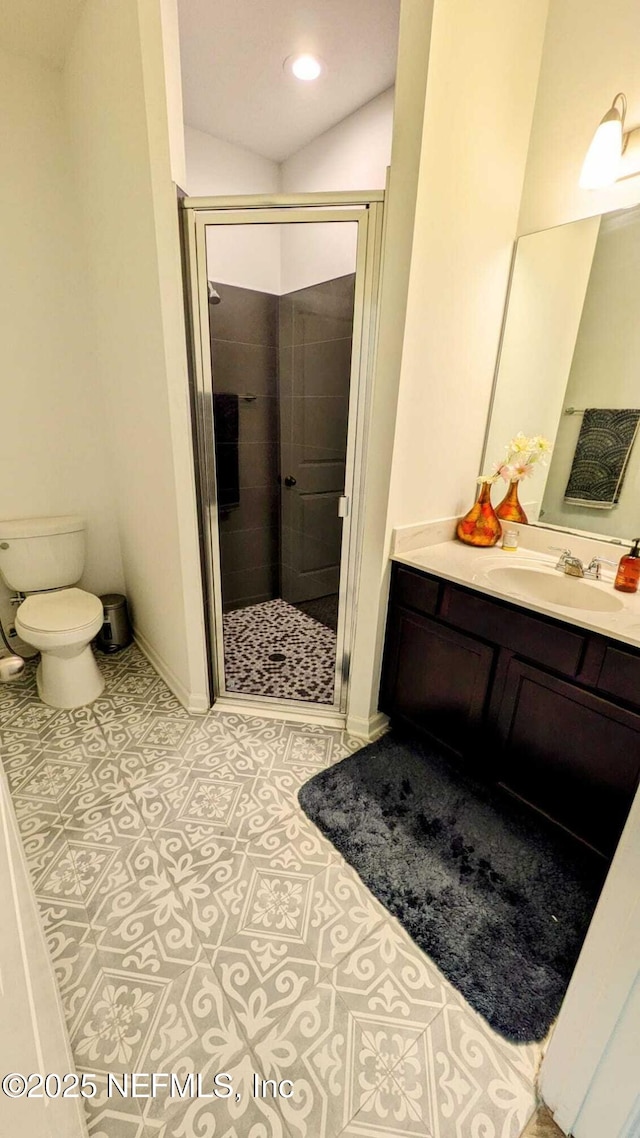 bathroom featuring a shower with door, vanity, tile patterned floors, and toilet