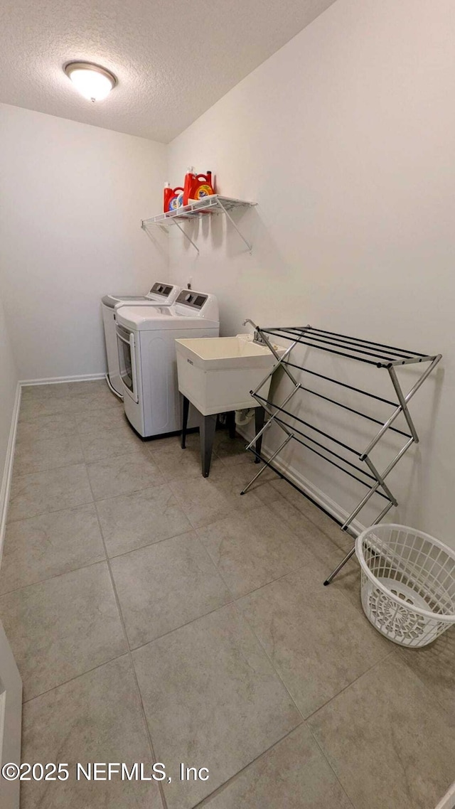 laundry area with sink, a textured ceiling, and independent washer and dryer