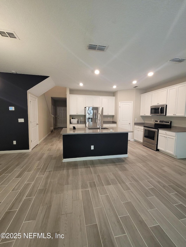 kitchen featuring white cabinetry, visible vents, a kitchen island with sink, and appliances with stainless steel finishes