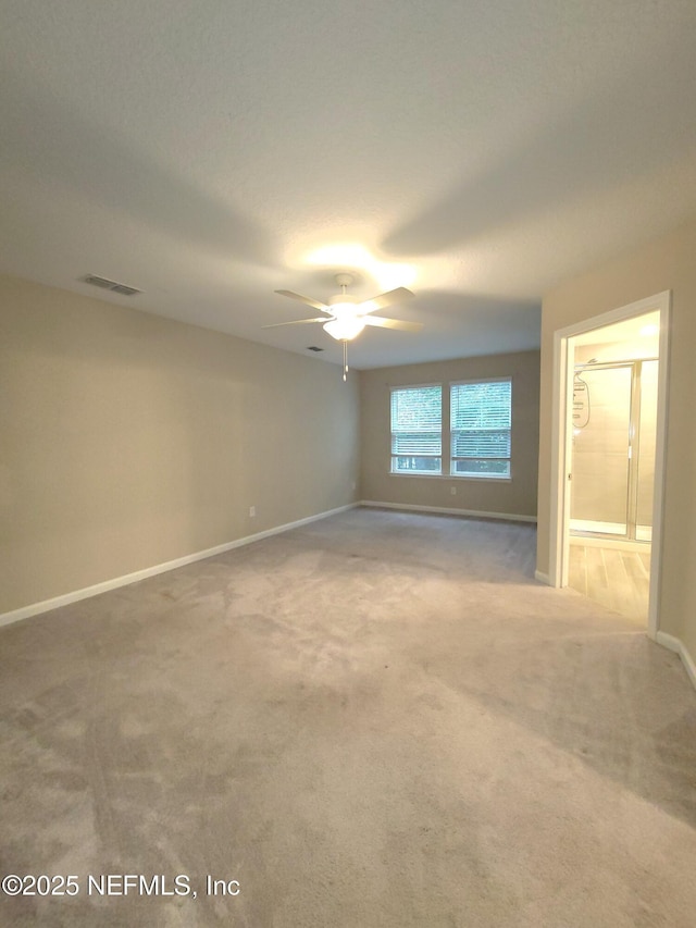 empty room featuring ceiling fan, light colored carpet, visible vents, and baseboards