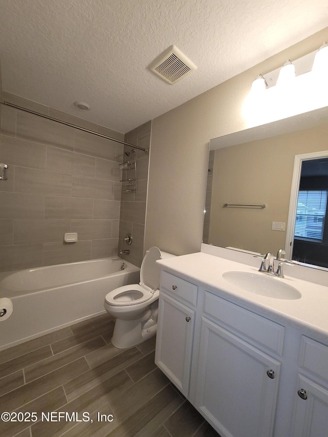 bathroom featuring visible vents, toilet, wood tiled floor, tub / shower combination, and a textured ceiling