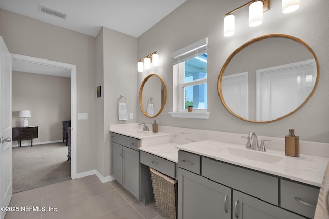 bathroom featuring baseboards, double vanity, tile patterned floors, visible vents, and a sink