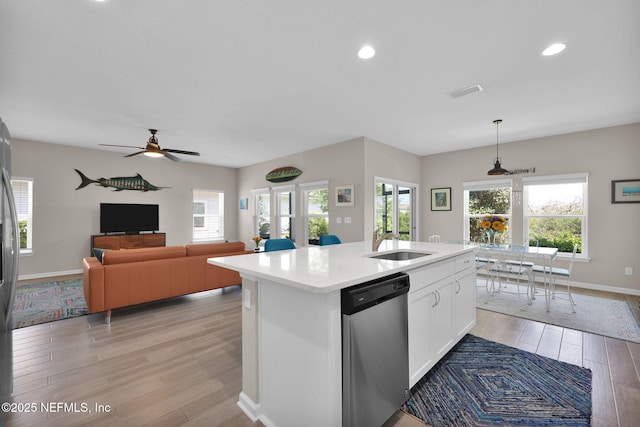 kitchen featuring light wood-type flooring, dishwasher, light countertops, baseboards, and plenty of natural light