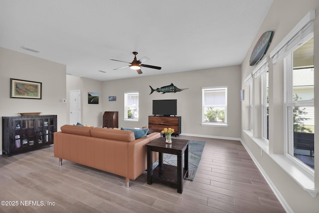 living room featuring light wood-style floors, baseboards, a ceiling fan, and visible vents