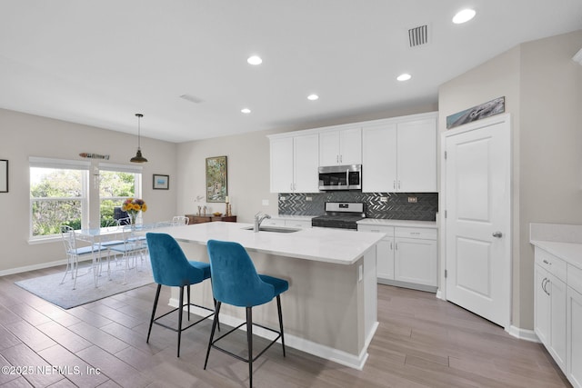 kitchen featuring visible vents, a sink, a kitchen breakfast bar, light wood-style floors, and stainless steel appliances