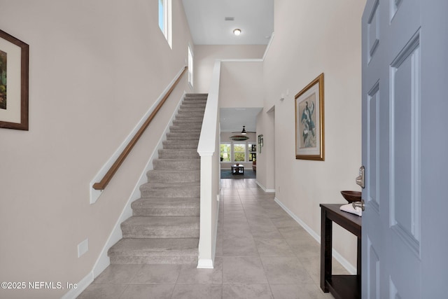 interior space featuring tile patterned floors, baseboards, and a towering ceiling