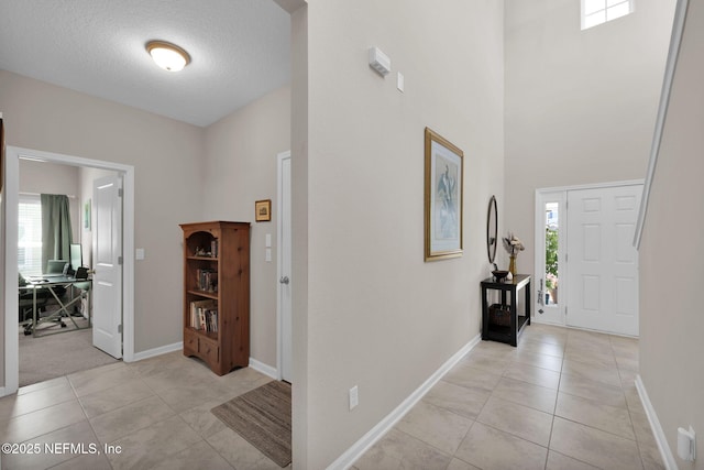 entrance foyer with a high ceiling, baseboards, light tile patterned flooring, and a textured ceiling