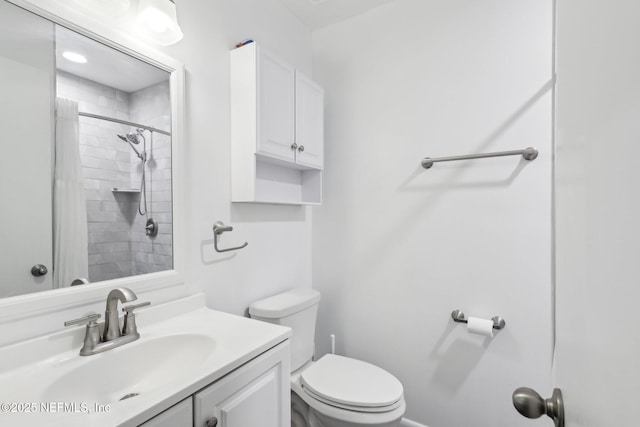 bathroom with toilet, vanity, and tiled shower