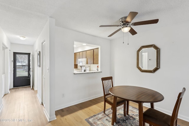 dining space with a textured ceiling and light hardwood / wood-style floors