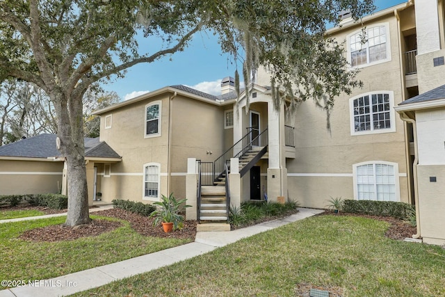 view of front of property with a front lawn, stairway, and stucco siding