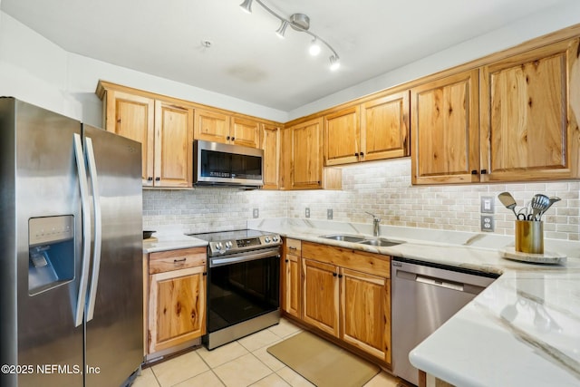 kitchen with a sink, appliances with stainless steel finishes, light countertops, light tile patterned floors, and decorative backsplash