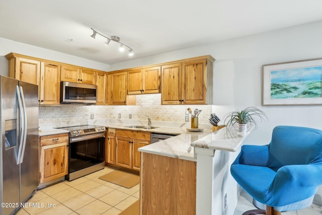 kitchen with backsplash, light tile patterned floors, appliances with stainless steel finishes, a peninsula, and a sink