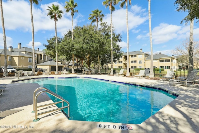 community pool with a patio area, a residential view, and fence