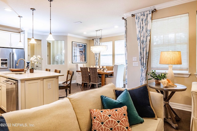 kitchen with an island with sink, sink, white cabinetry, and decorative light fixtures