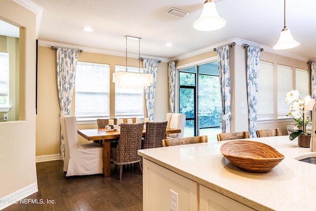 kitchen featuring dark wood-type flooring, crown molding, light stone counters, and pendant lighting