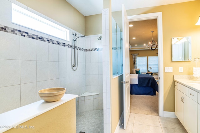 bathroom with vanity, a chandelier, tile patterned flooring, and a tile shower